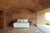 Bedroom, Travertine, Concrete, Bed, and Night Stands A look inside the master bedroom with a vaulted ceiling.   Bedroom Travertine Photos from A Sculptural Holiday Home is Shaped by the Peruvian Desert