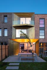 Outdoor, Wood, Grass, Horizontal, Concrete, Hardscapes, Back Yard, Large, and Landscape The fenced-in backyard includes outdoor dining and a small green-roofed storage unit.  Outdoor Wood Landscape Hardscapes Back Yard Photos from A Sculptural Brass House Glows Like a Jewel in Amsterdam
