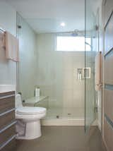 Porcelain tiles line the bathroom. The countertops and cabinetry are ceramic and wood veneer over fiberboard, respectively.