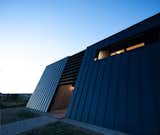 Exterior, Metal, House, Metal, Concrete, Wood, and Saltbox "Both the deep-set windows and the brise soleil, in addition to the back canted wall, help to control solar gain."  Exterior Metal Wood Saltbox Concrete Photos from A Folded Steel Roof Shields a Fortress-Like Abode in Nova Scotia