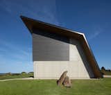 Exterior, Metal, Wood, House, Metal, Concrete, and Saltbox In contrast to its heavily glazed north facade, the home's other three sides are closed off from view for privacy.  Exterior Metal Saltbox Metal House Photos from A Folded Steel Roof Shields a Fortress-Like Abode in Nova Scotia