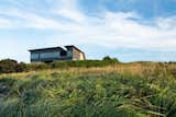 Exterior, Metal, Metal, Concrete, House, Wood, and Saltbox Located on the southern shore of Nova Scotia in Kingsburg, Treow Brycg is set in wild landscape of rocks, the sea, and tall grasses.  Exterior Saltbox Metal House Wood Photos from A Folded Steel Roof Shields a Fortress-Like Abode in Nova Scotia
