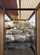 Outdoor, Small Patio, Porch, Deck, Walkways, Boulders, and Metal Patio, Porch, Deck A glimpse of the breezeway beneath the grated metal footbridge. The doors and accents were constructed from ipe wood.  Photo 6 of 12 in An Award-Winning Writing Studio Hides Quietly in Texas