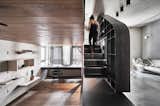 The black staircase and storage wall act as a threshold between the bedroom/office and the living spaces. Concrete-like faux finishes were used for the walls and floors of the living spaces.