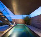 The swimming pool's dark tile finish mirrors the cantilevered container above it.