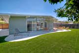 Outdoor, Back Yard, Grass, Large Patio, Porch, Deck, Trees, Vertical Fences, Wall, Stone Patio, Porch, Deck, Concrete Patio, Porch, Deck, and Wood Fences, Wall The large roof overhang protects the newly added amoeba-shaped patio and fire pit. The house sits on a flat 6,400-square-foot lot.   Photos from Grab This Light-Filled L.A.  Midcentury by A. Quincy Jones For $629K