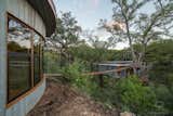 Outdoor, Grass, Shrubs, Trees, Hanging Lighting, Small Patio, Porch, Deck, and Wood Patio, Porch, Deck A 60-foot-long suspension bridge links the treehouse with the detached bathhouse.  Photos from Escape to the Texan Treetops in This Eco-Luxe Treehouse