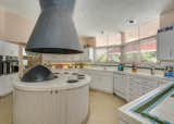 An oversized hood and a circular cooktop station is located in the round kitchen. 