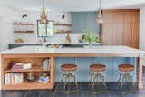 The custom shaker style cabinets were painted Benjamin Moore Knoxville Gray and mixed with walnut cabinets with an island overhang by Elite Remodeling Concepts, LLC. The stools are from Dovetail Furniture.
