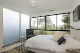 This guest room gets drenched in sunlight thanks to full-height frosted glass windows and operable glazing overlooking the city below. 