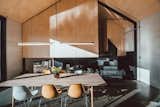 The dining area is located a split-level above the kitchen in Nik and Emma's home. The plywood-clad volume above houses the master bedroom.