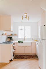 At a renovated home in Pennsylvania, the orange kitchen countertops were swapped for custom concrete countertops. The cabinets were painted Pink Ground by Farrow & Ball and paired with Build.com hardware, giving the kitchen a warm glow, in particular thanks to the natural light coming in from the double exposure of the windows. The kitchen sink and faucet are from Amazon, while the tile is from Lowes.