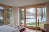 The largest guest bedroom is surrounded by walls of glass framing views of Candlewood Lake.