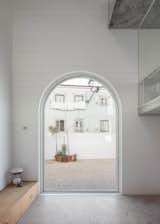 Fitted with glass, a massive arched pivot door, made by Much More than a Window, provides access to the outdoor patio. 