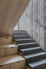 Poured concrete stairs step down alongside built-in storage. 