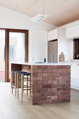 The repurposed bricks, which were hand-cleaned by the clients, make another appearance as the anchored island bench. The countertop is Caesarstone, and the stools are Lightwood high stools by Jasper Morrison.