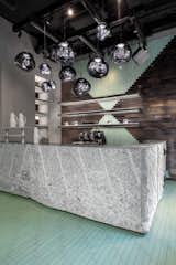 The entrance features a bar made from monolithic granite offcuts. The rough-cut granite is complemented by sleek lava stone tiles and Opal lights. 