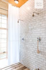 The showers are lined with Carrara subway tile from TheBuilderDepot and a wooden slat floor. 