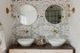 To complete the boho feel, the designers added an Urban Outfitters wallpaper behind the double vanity. The handmade brass fixtures are from Pepe & Carols.