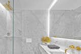 Slabs of Carrara marble cover the minimalist bathroom, which is punctuated with fixtures made from unlacquered brass. 