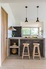 The breakfast bar from the original home was given a modern refresh. The existing stools were refinished and paired with concrete countertops. Designer pendant lights hang from above.