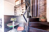 A custom laser-cut steel balustrade features a pattern that relates to the existing brick wall and provides privacy. The black cork kitchen tile extends into the addition, where it is used on the stairs and bathroom floor.