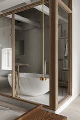 A view of the bathroom with a freestanding tub and brass fixtures from the bedroom area.