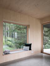 In the living room, a large window frames views of the pine forest in the north. The door leads to the south-facing outdoor terrace.