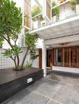 Pantang Studio transformed a three-story building in Bangkok into a flexible residence that can serve as a single home or a duplex. The flowering plumeria tree, which came with the original property, was preserved in the redesign.
