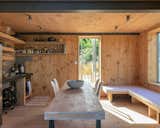 The simple kitchen is located beneath the mezzanine. The dining tabletop was made from a cross-laminated timber off cut, while the bench, which was designed and built by O’Connell, can be transformed into a double bed. 