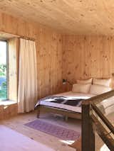 A glimpse inside the main bedroom. Cross-laminated timber lines the walls, ceilings, and floors to create a "solid, warm enclosure," shares the couple. "The use of exposed structural panels significantly reduced the number of components and waste from finishing trades."