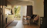 The minimalist eat-in kitchen features gray glulam cabinetry. A larger dining table is located on the deck.