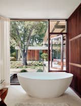 Walls of glass blur the boundary between indoors and out in this bathroom. The floors are Jerusalem Bone limestone.