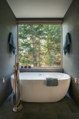 The shared wet room features a Boyce freestanding tub by Signature Hardware with west-facing views of the forest.
