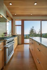 A large, east-facing window in the kitchen captures morning light. The kitchen is outfitted with Caesarstone Pebble countertops, a Heath Ceramics Lichen backsplash, and Smith & Vallee Woodworks cabinetry.