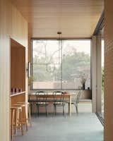 A bronze mesh veil fitted to the dining room window provides privacy while allowing for views of the street and the corrugated garages that inspired the exterior walls. The space is furnished with a Boyd table from KFive + Kinnarps Australia, Thonet No. 18 dining chairs, Schiavello Furniture stools as well as lights by Neri&amp;Hu and CRITERIA. 