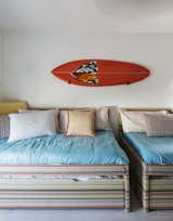 In the boys’ shared room, the Novogratzes wrapped a pair of IKEA trundles with Jonathan Adler fabric. The bright-orange surfboard provides a vibrant contrast of color to the blue bedding. 