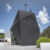 Exterior, House Building Type, Metal Roof Material, and Metal Siding Material Built mainly from steel, the multifaceted Origami House features a matte, all-black finish that distinguishes the building from its neighbors.   Photo 2 of 8 in A Family in Poland Adds an Origami-Inspired Retreat to Their Backyard