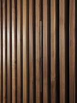 A close-up of the wood walls. Acoustic felt is set between the slats, which improve acoustics and hide doors and storage space. Here, the door pull to the master bedroom is hidden in the wall, which retracts like an accordion.