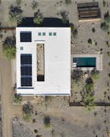 The 15.12 kW Tesla solar array that tops the reflective white roof is hidden from view on the ground. The solar panels provide enough power for the home and cars for most of the year; Tesla Powerwall batteries store excess energy. Also pictured is a vegetable garden at the top right corner. 