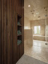 A glimpse inside the limestone-clad steam shower in the master suite. The walnut slat walls hide storage with cubbies for towels. 