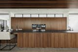 Clerestory windows above built-in walnut cabinetry and a wall of glazing on the south side bring natural light into the kitchen, located at the heart of the living space. The kitchen countertop is Dekton Domoos. 