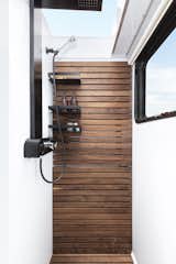 All Living Vehicle showers measure 32 inches by 36 inches with a clear skylight above. The optional Spa Bathroom upgrade includes a rear hardwood slatted wall with shelving, macerator with bidet or compost toilet, towel warmer, outdoor shower, and a shower seat. 