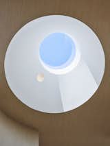 A circular skylight bathes the staircase in light and views of a changing sky. 