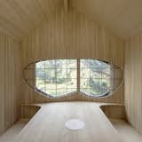 A U-shaped wooden bench wraps around the table used for tea ceremonies. The three-part sliding window is handmade with leaded glass and frames south-facing views of the forest. 