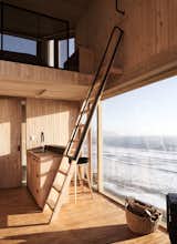 A wooden ladder leads up to the loft bedroom. A wood-burning stove provides heating.