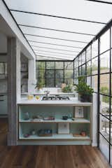 Kitchen, Medium Hardwood Floor, Colorful Cabinet, Wood Cabinet, Engineered Quartz Counter, Marble Backsplashe, Cooktops, and Undermount Sink A greenhouse-like facade was created, connecting the verdant outdoors with the kitchen and living area.   Photo 5 of 14 in C Studio Apartment by This is IT