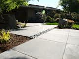 Concrete slabs and black beach pebbles combine to create a modern path to the front door.