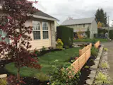 Local basalt retaining wall and cedar screens add privacy to this corner lot landscape.