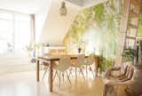 bright dining area with wooden furniture, live plants, and forest wallpaper
